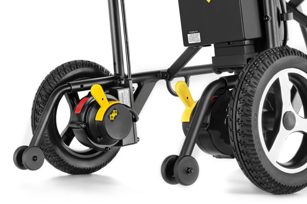 Porto Mobility Ranger Skylight folding power wheelchair, rear wheel hubs with yellow levers and anti tip wheels close up